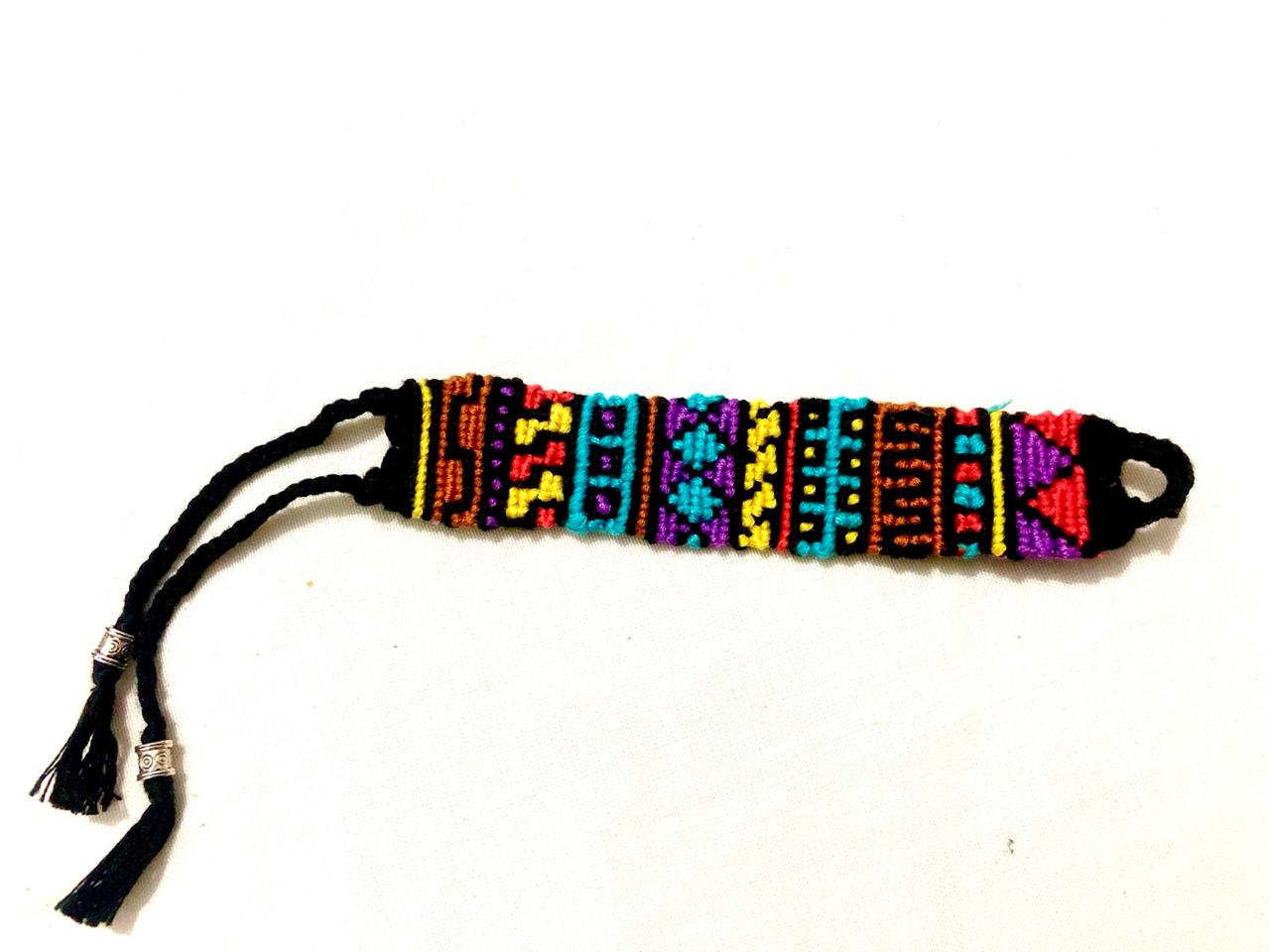 Handmade multicolor macramé bracelet with geometric tribal-inspired patterns, black braided ties, and silver bead accents.