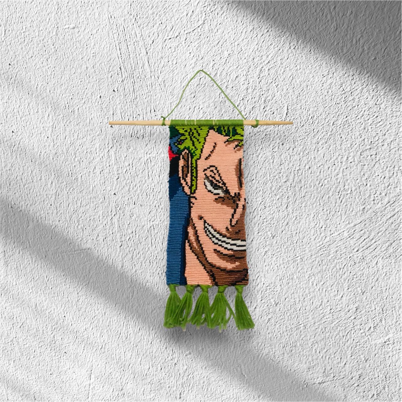 Handwoven macramé wall hanging inspired by Zoro from One Piece, featuring his green hair, confident grin, and green tassel finish